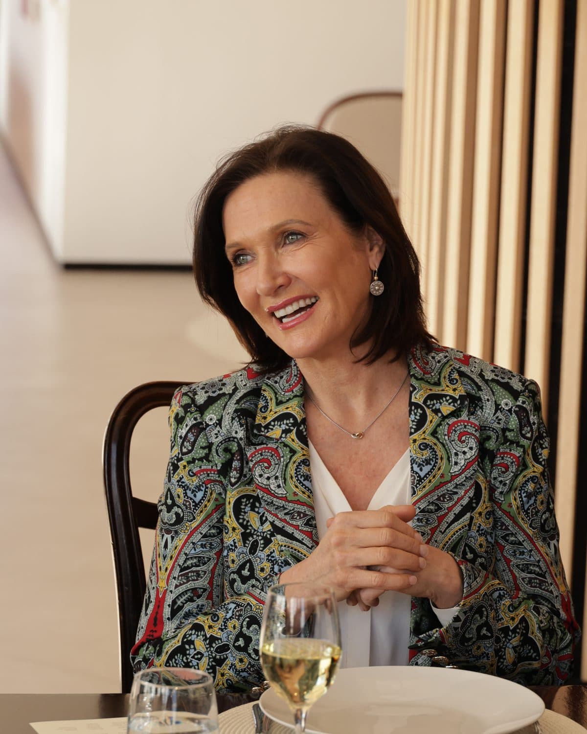 Dr. Margie Warrell, seated at a table, smiling mid-conversation.